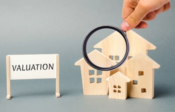 'valuation' sits adjacent to a colony of homes, which is magnified by a glass at hand