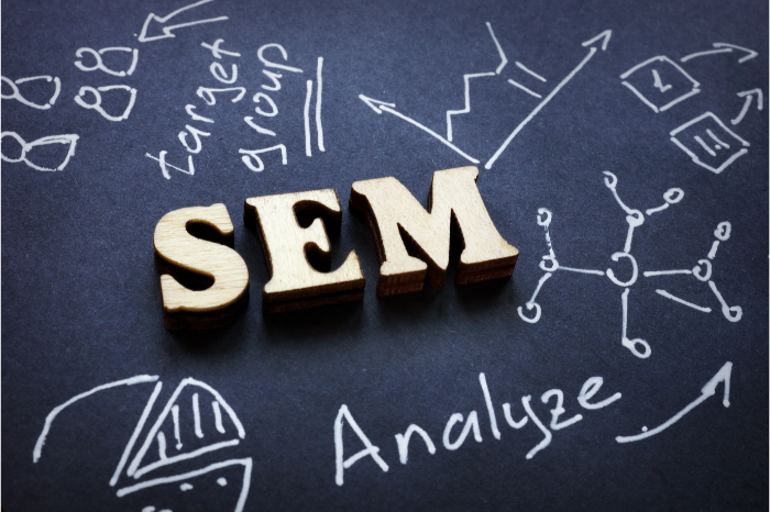 slat containing scattered faint representations of terms 'analyze' and 'target group' via personas, chemistry, pie-chart, and line-graph, focuses on the central and bolded letters of 'S' 'E' 'M'