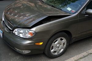 A car with bent in hood from a fender bender in a parking lot. 
