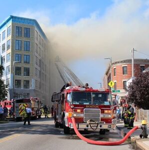A hotel that is on fire with fireman trying to put it out. 