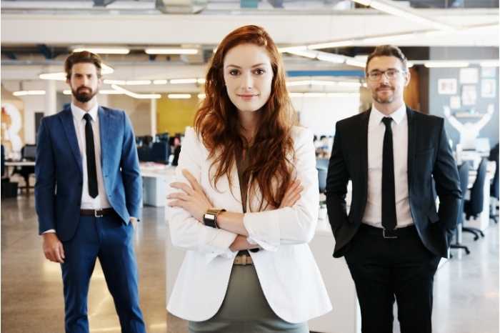 A group of three professionals standing in a well-lit office.